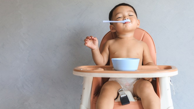 child eating food sitting in a high chair
